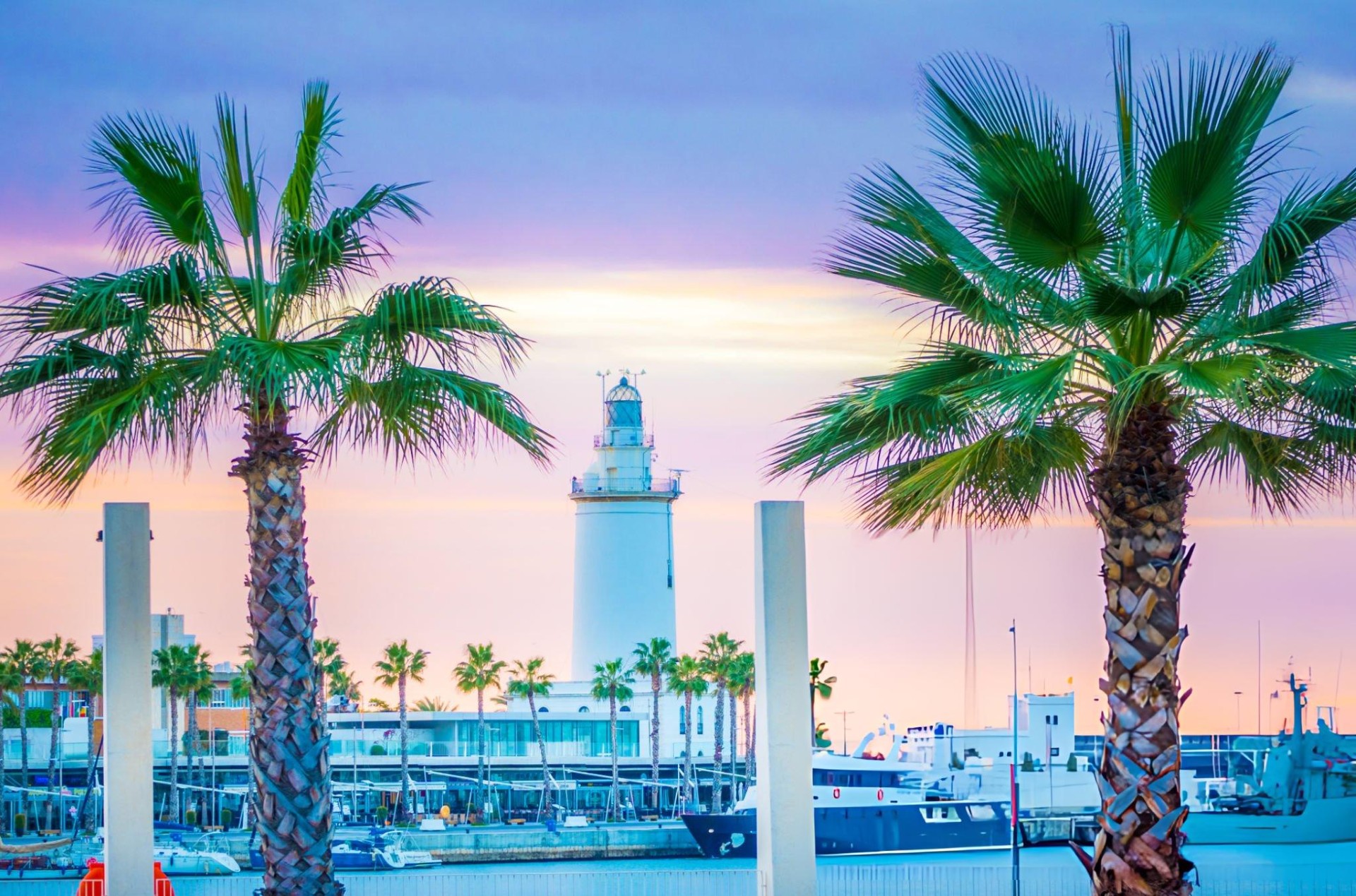 La Farola lighthouse and palm trees at the port of Malaga, next to Malagueta Beach