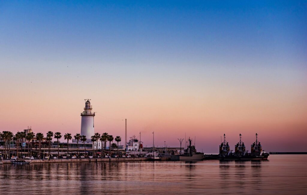 La Farola lighthouse and the port of Malaga at dusk, next to La Malagueta